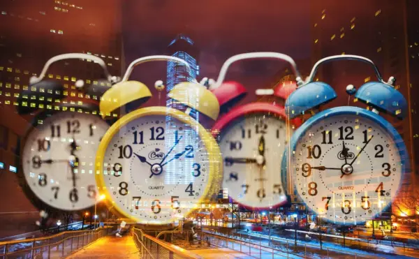Wiele kolorowych budzików na tle nocnego miasta. 0404 znaczenie czasu, który nieustannie płynie.
